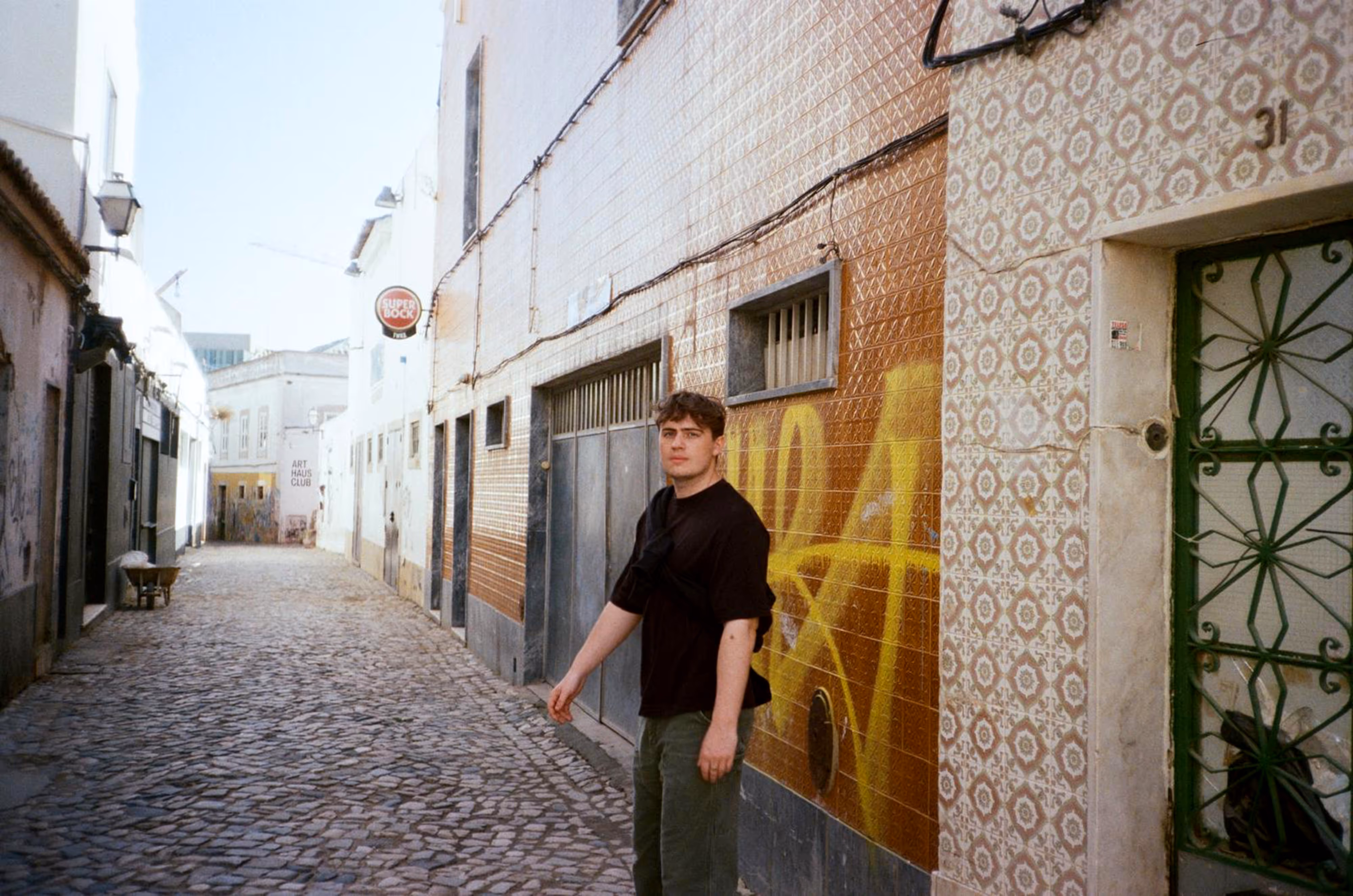 Me on cobblestone street against colourful tiled building with patterned facade and shuttered windows.